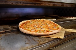 fresh pizza being brought out of the oven. 